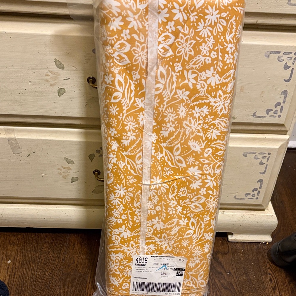 Bolt of gold and white floral fabric.